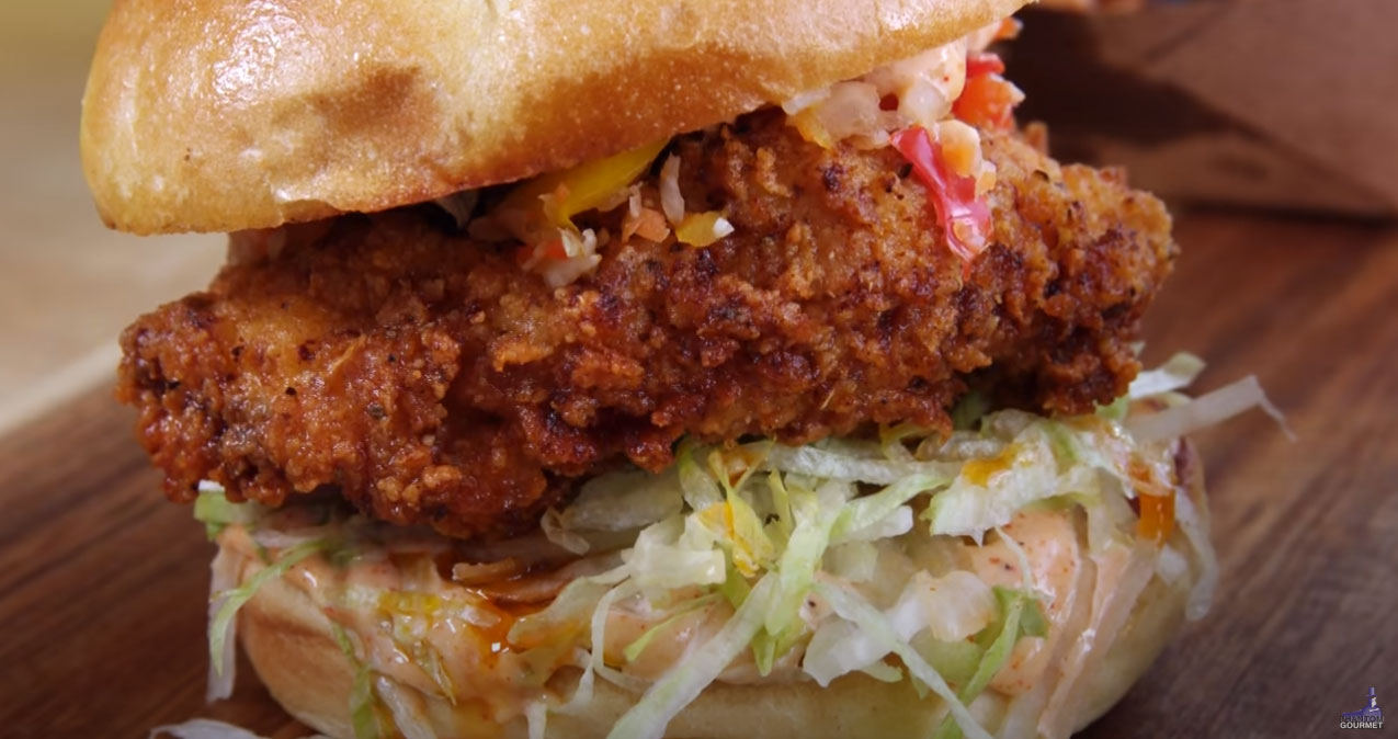 This is an image of a Flip the Bird fried chicken sandwich in MA. It is cooked to perfection and topped with lettuce and sauce.